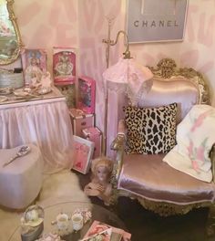 there is a doll sitting in the corner of this room with pink furniture and accessories