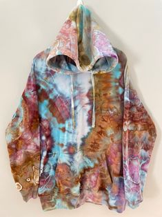 a tie dye hoodie is hanging on the wall with it's hood pulled up