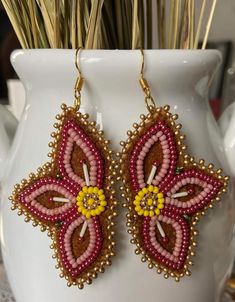 a pair of beaded earrings sitting on top of a white vase