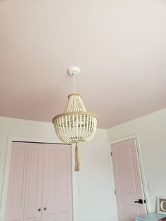 a white chandelier hanging from the ceiling in a room with pink walls and doors