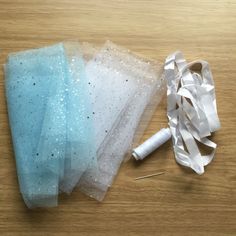 two pieces of tulle sitting on top of a wooden table next to a pair of scissors