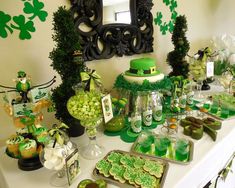 a table topped with lots of green desserts and cupcakes on top of it