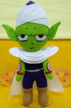 a green stuffed toy with a white hat and blue pants on it's head