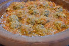 a pot filled with meatballs and sauce sitting on top of a stove burner