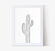 a black and white drawing of a cactus in a frame on the wall next to a plant