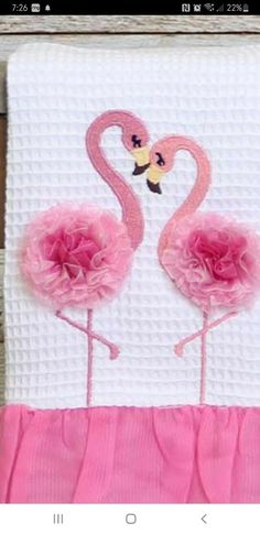 two pink flamingos on a white towel with ruffles and a yellow butterfly