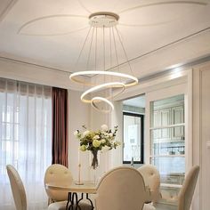 an elegant dining room with white chairs and round chandelier