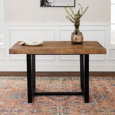 a wooden table with metal legs and a vase filled with flowers sitting on top of it