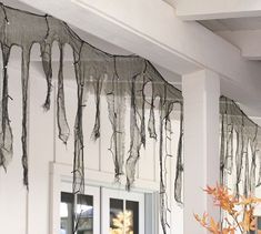 some branches are hanging from the ceiling in front of a window with curtains on it