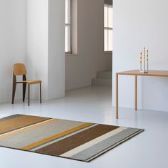 a chair and table in a room with white walls, flooring and rugs