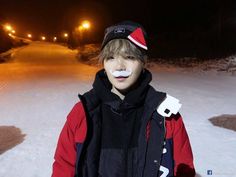 a young man standing in the snow at night with his nose painted like santa clause