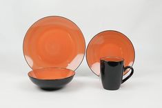 an orange and black dinnerware set on a white background with a black coffee cup