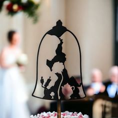 a close up of a wedding cake with a bell on it and a bride in the background