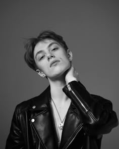 black and white photograph of a woman in a leather jacket with her hands on her neck