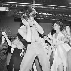 black and white photograph of people dancing at a party with one person covering his face