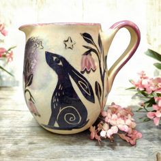 a coffee cup with an image of a rabbit on it and flowers in the background