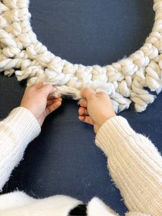 someone is crocheting a knitted wreath with yarn