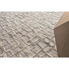 an area rug with squares and lines in grey tones on a wooden table, close up