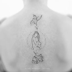 the back of a woman's neck with three images of flowers on her left shoulder