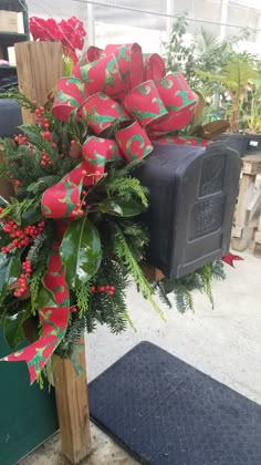 a christmas wreath on top of a mailbox decorated with holly and red bowes