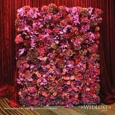 a red and purple flowered wall on top of a wooden floor in front of a red curtain