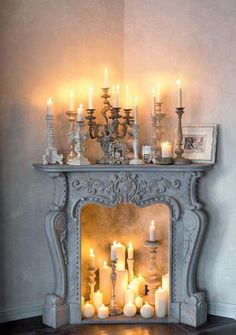 a mantel with candles and pictures on it in front of a wall mounted fireplace