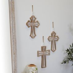 three wooden crosses are hanging on the wall next to a vase with flowers in it