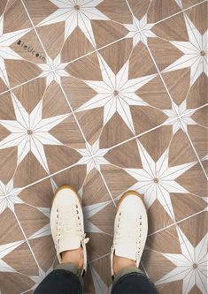 a person standing on top of a tiled floor next to a pair of white shoes