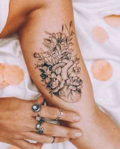 a woman's arm with flowers on it and a ring in the middle of her hand