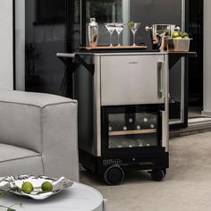 a bar cart with drinks on it in front of a couch