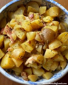 a blue and white bowl filled with potatoes on top of a wooden table