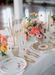 the table is set with flowers and goldware for an elegant dinner or reception party