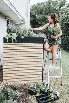 a woman sitting on top of a chair next to a planter filled with plants