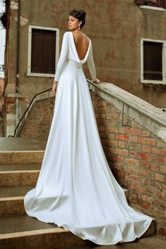 a woman in a white wedding dress standing on some steps with her back to the camera