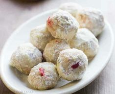 a white plate filled with powdered sugar covered donuts on top of a wooden table