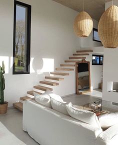 a living room with white furniture and wooden stairs