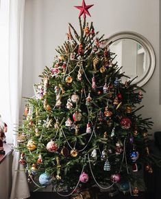 a christmas tree with ornaments on it in front of a mirror