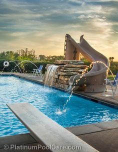 an outdoor pool with a slide and water features