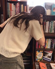 a woman standing in front of a book shelf filled with books