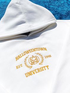 Prepare to immerse yourself in the enchanting spirit of Halloween with our Halloweentown University Embroidered Oversize Hoodie. This extraordinary hoodie is the ultimate addition to your spine-tingling seasonal attire, tailor-made for those who revel in the magic of the holiday or simply harbor a passion for all things otherworldly and enigmatic. Join the prestigious ranks of Halloweentown University and immerse yourself in the unparalleled allure of Halloween. Whether you're en route to a thri White Hoodie With Embroidered Graphics For Fall, Embroidered Hoodie For Fall Streetwear, White Hoodie With Custom Embroidery For Fall, Cotton Halloween Hoodie With Adjustable Hood, Halloween Cotton Hoodie With Adjustable Hood, Halloween Cotton Sweatshirt With Adjustable Hood, White Drawstring Hood Sweatshirt For Halloween, Halloween White Sweatshirt With Drawstring Hood, Hooded Embroidered Sweatshirt For Halloween