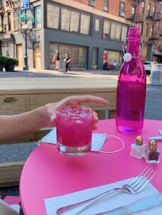 a pink table topped with a glass filled with liquid