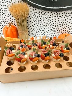 an assortment of fruit and cheeses in small bowls on a tray with pumpkins