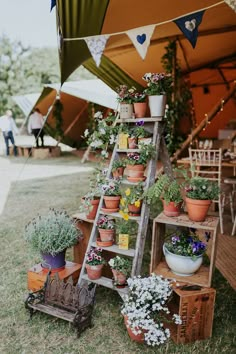 a wooden ladder with potted plants on it in front of some tables and chairs