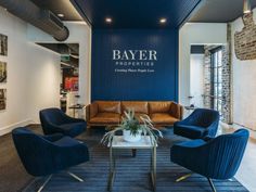 an office lobby with blue walls and leather chairs in front of the wall that says bayer properties