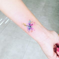 a small dragonfly tattoo on the wrist