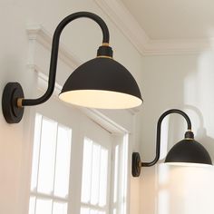 two black and white lights hanging from the side of a wall