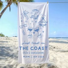 a towel hanging from a clothes line on the beach with palm trees in the background