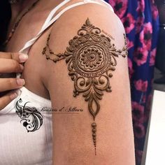 a woman's arm with a henna tattoo on the back of her shoulder