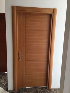 an open wooden door in a room with marble flooring and white walls on either side