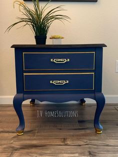 a blue dresser with gold trim on it and a potted plant in the corner